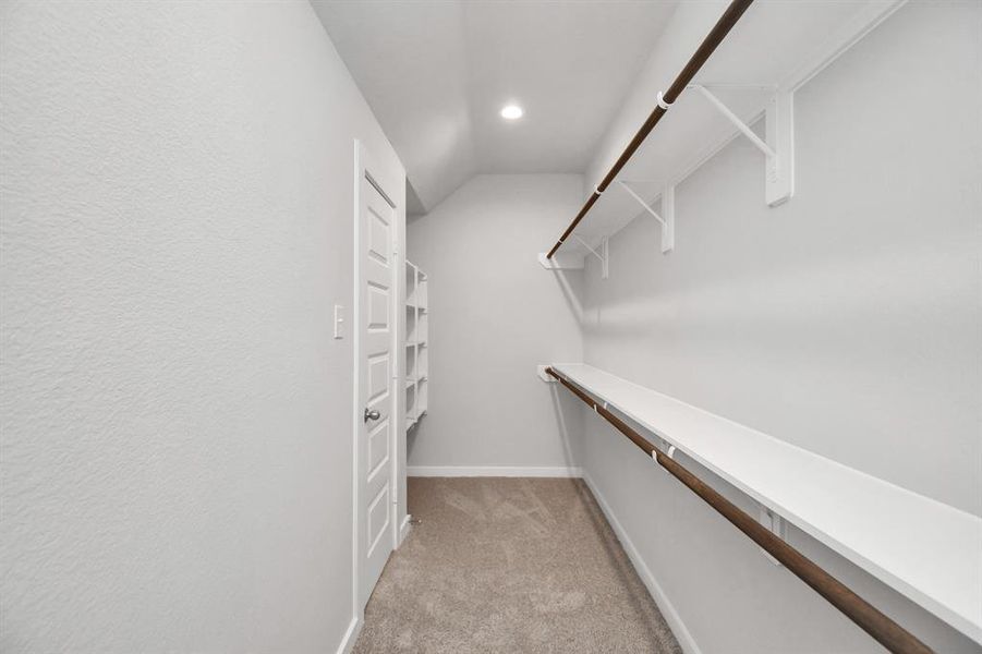 Walk-in closet that epitomizes luxury and practicality. This generously sized space features built-in shelving, offering abundant room for impeccable organization. High ceilings and recessed lighting create a bright and welcoming ambiance. Photo shown is example of completed home with similar plan.