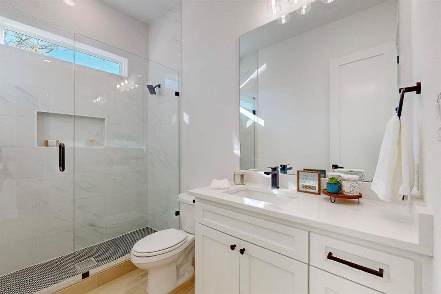 Bathroom with hardwood / wood-style flooring, a shower with door, vanity, and toilet