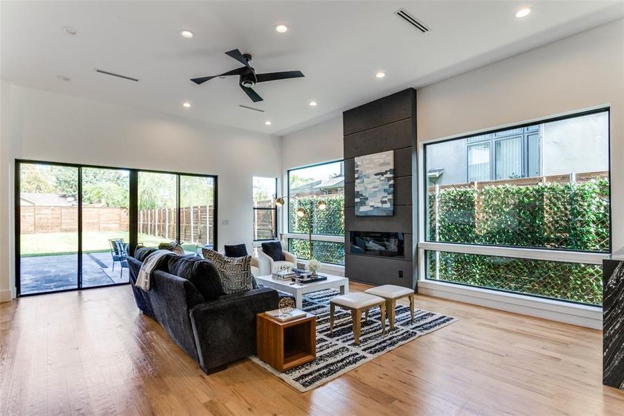 Living room with a large fireplace, light hardwood / wood-style floors, and ceiling fan