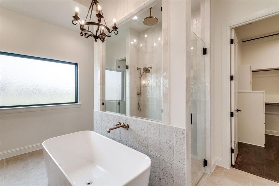 Bathroom with tile patterned floors, separate shower and tub, sink, and a chandelier