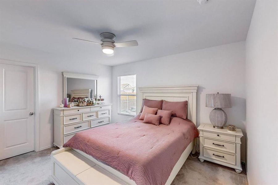 Carpeted bedroom featuring ceiling fan