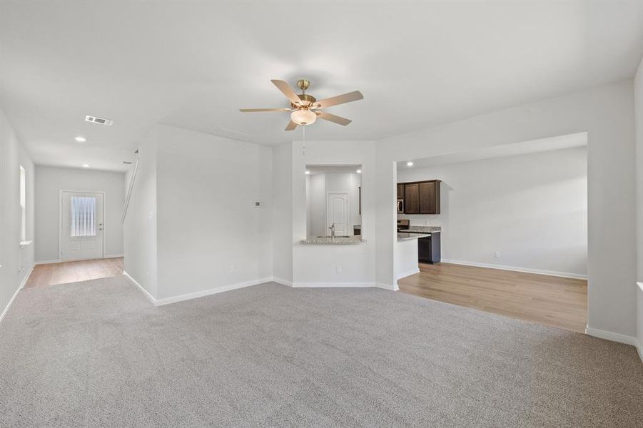 Unfurnished living room with ceiling fan, sink, and light wood-type flooring