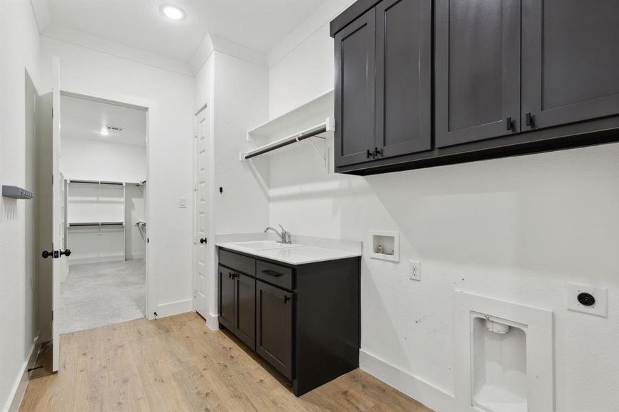 Laundry area featuring cabinets, hookup for an electric dryer, sink, light hardwood / wood-style flooring, and hookup for a washing machine