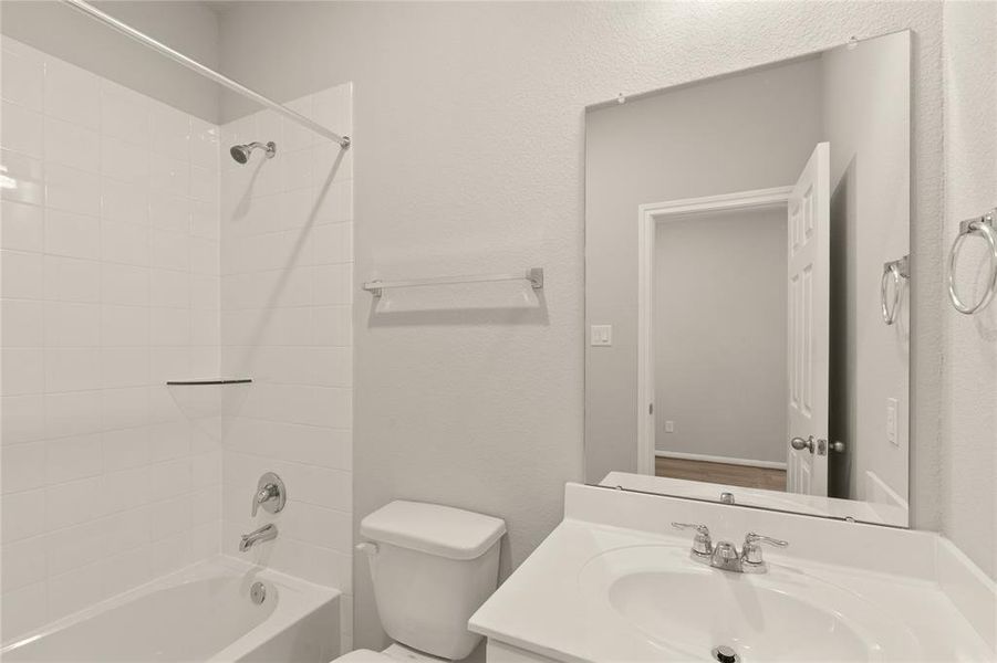 The secondary bath features tile flooring, white cabinetry and light countertops and a shower/tub combo. Perfect for accommodating any visiting family and friends.