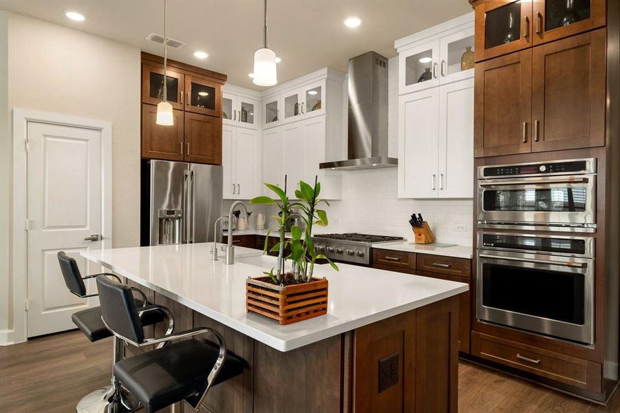 This stunning kitchen displays such a beautiful contrast with the dark stained lower cabinets and bright white feature cabinets, neutral paint, Quartz countertops, light modern backsplash, and built in SS appliances, oversized kitchen island with extra storage, breakfast bar, recessed lighting, high ceilings and spacious pantry.