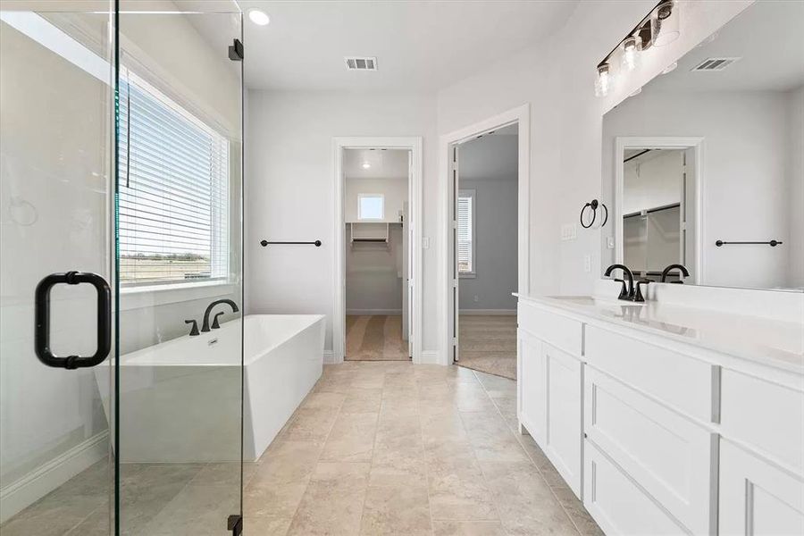 Bathroom featuring shower with separate bathtub, vanity, and tile patterned flooring