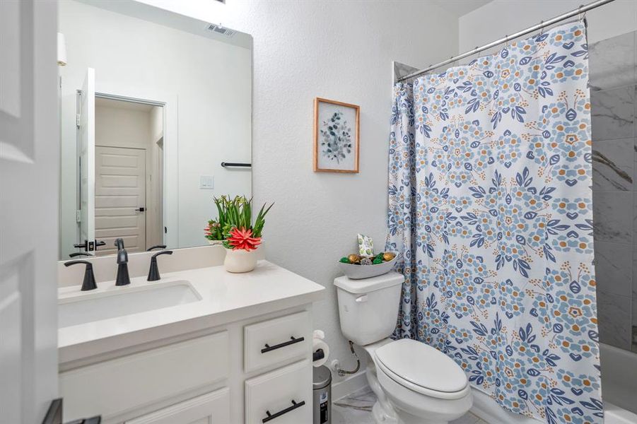 The downstairs full bathroom with white cabinets, a spacious tub and shower, and large vanity, is located off the downstairs secondary bedroom, making it a perfect place for guests to unwind.