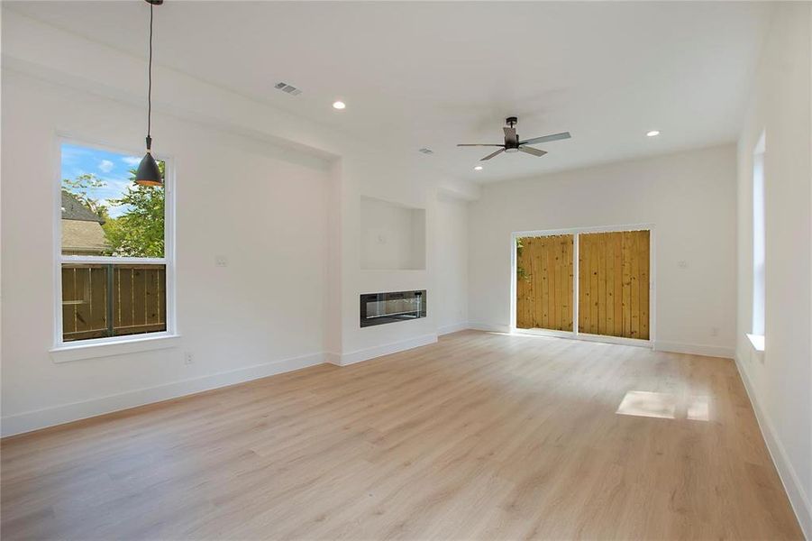 Unfurnished living room featuring heating unit, light wood-type flooring, and ceiling fan