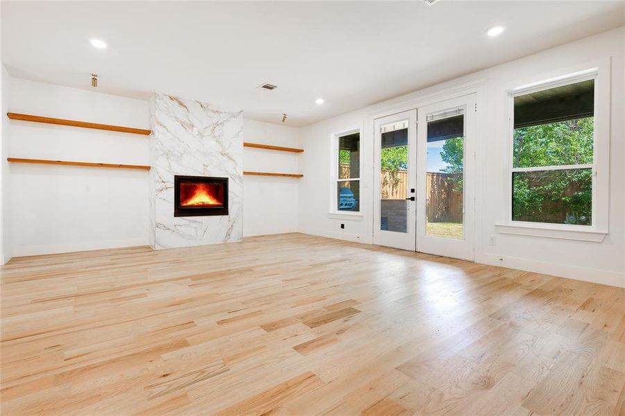 Unfurnished living room featuring a premium fireplace, light hardwood / wood-style flooring, and french doors