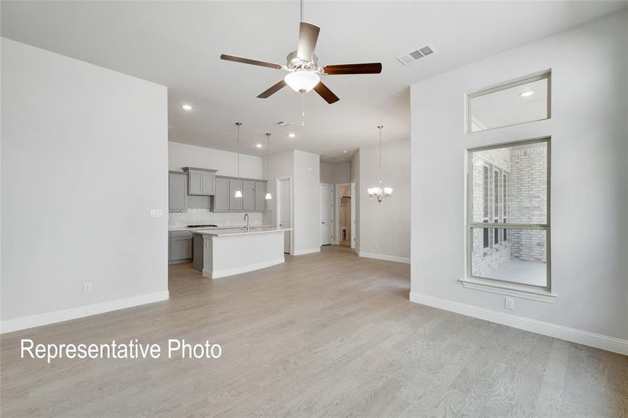 Unfurnished living room with ceiling fan with notable chandelier, light wood-type flooring, and sink