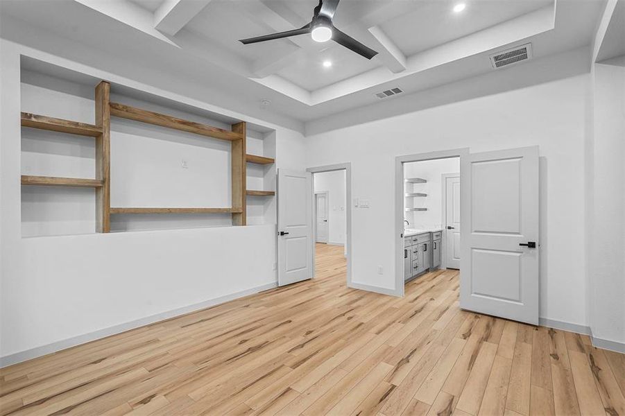 Unfurnished bedroom featuring light wood-type flooring, coffered ceiling, connected bathroom, ceiling fan, and beam ceiling