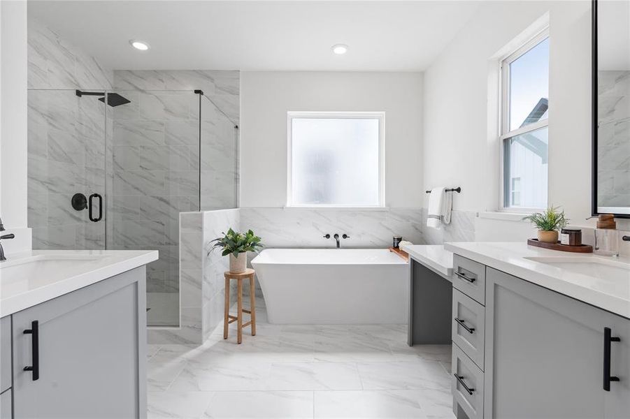 The spacious primary ensuite boasts a frameless shower, a stand-alone tub, and separate his-and-her sinks with dedicated vanity sections, exuding luxury and offering a personal sanctuary for relaxation and rejuvenation.