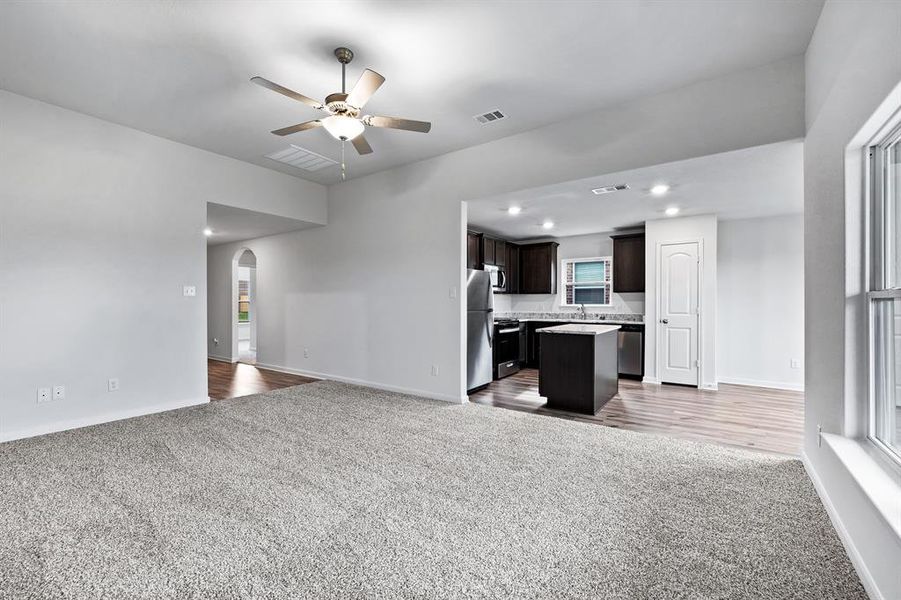 Unfurnished living room with light carpet, sink, and ceiling fan