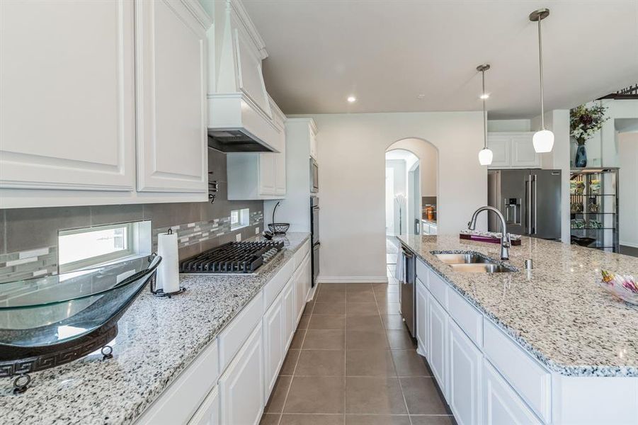 Kitchen featuring tile patterned flooring, tasteful backsplash, white cabinets, appliances with stainless steel finishes, and sink