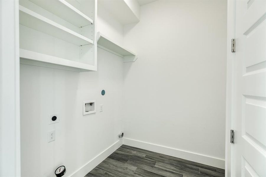 Laundry with built in shelves leads to the garage