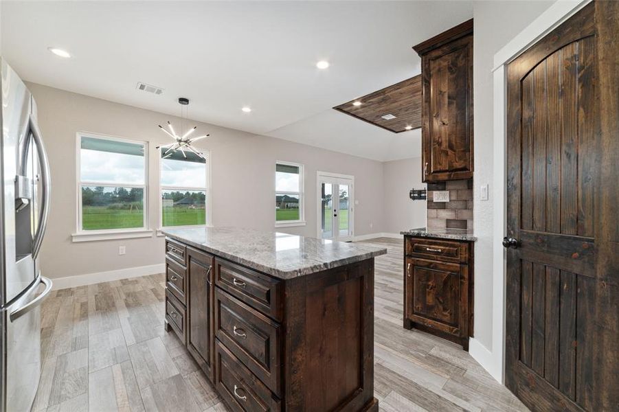 An alternate view highlights the connectivity between the kitchen and living area, enhancing the flow of everyday life. Conveniently placed wall outlets above the counters add practicality and ease during meal preparation and cooking, ensuring everything is within reach for your culinary endeavors.