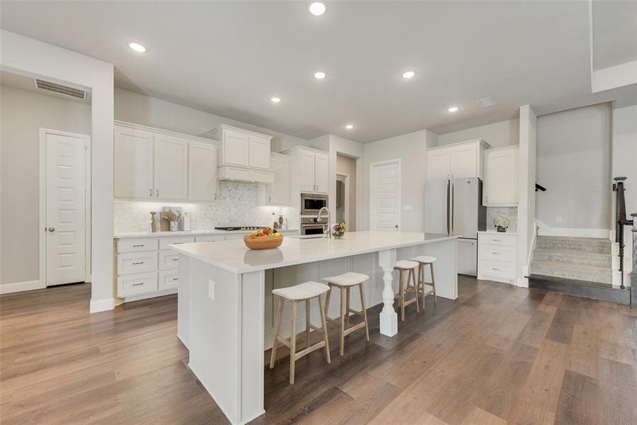 Kitchen featuring white cabinets, an island with sink, and appliances with stainless steel finishes