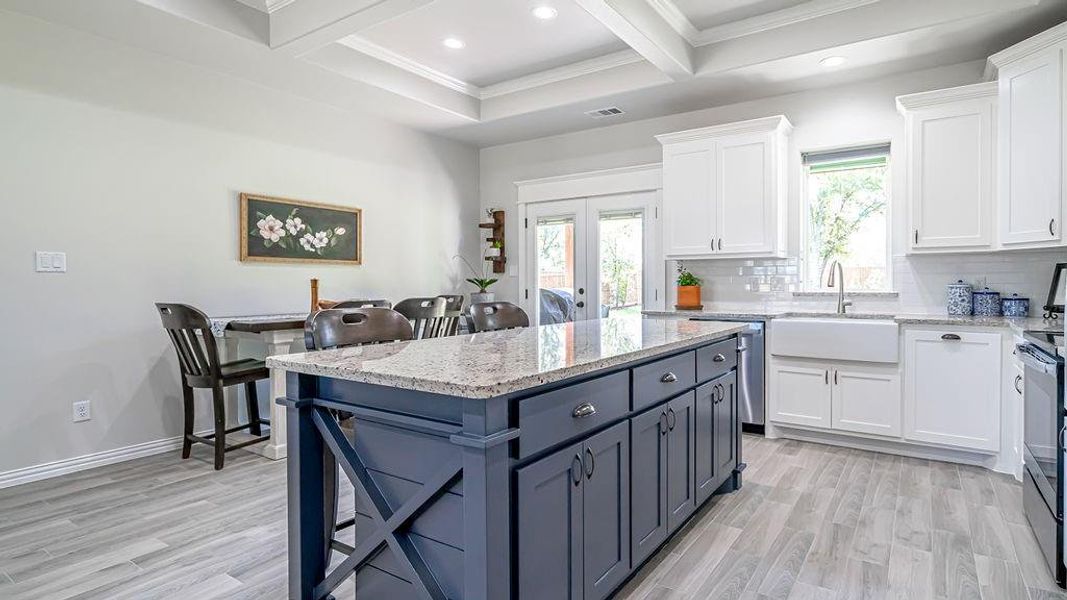 Kitchen featuring light wood-type flooring, tasteful backsplash, light stone counters, and white cabinets