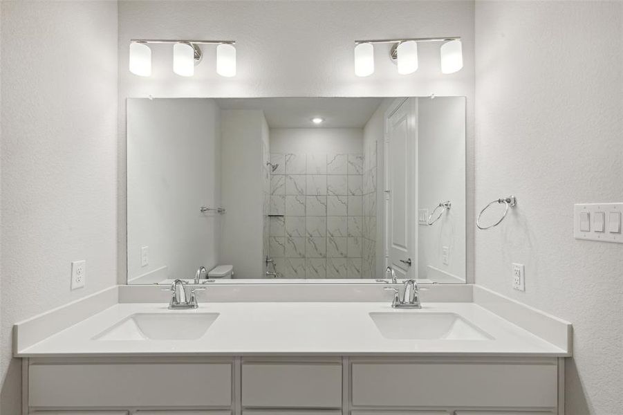 Bathroom featuring double sink, toilet, and large vanity