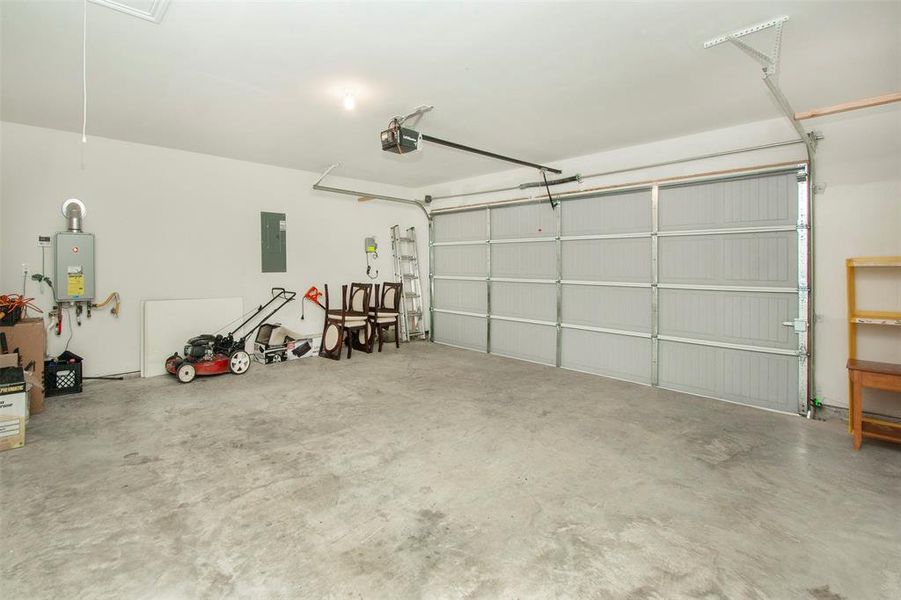 Garage with tankless water heater, electric panel, and a garage door opener