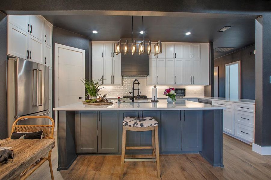 Kitchen with hardwood / wood-style floors, white cabinetry, hanging light fixtures, and high end fridge