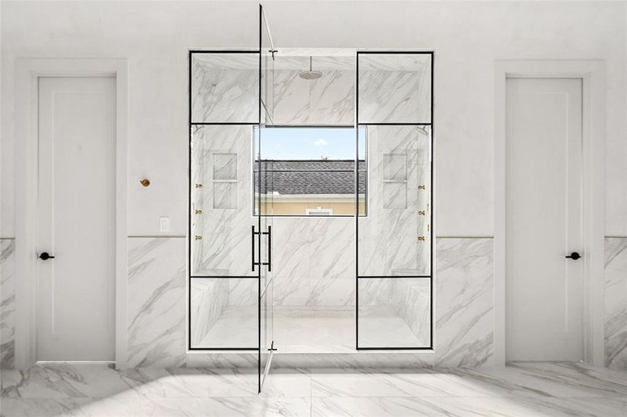 The stunning oversized shower features porcelain walls, a luxurious rainfall showerhead, and a separate dual showerhead system for the ultimate spa-like experience.