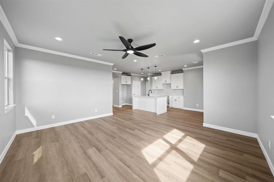 Unfurnished living room with sink, ceiling fan, crown molding, and light hardwood / wood-style flooring