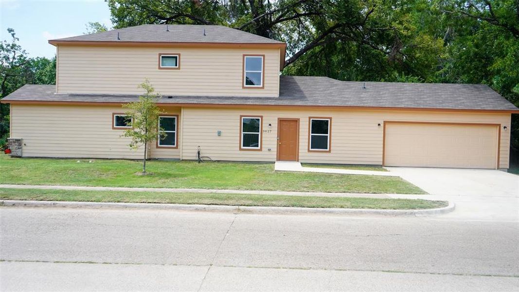 View of front facade featuring a garage and a front lawn