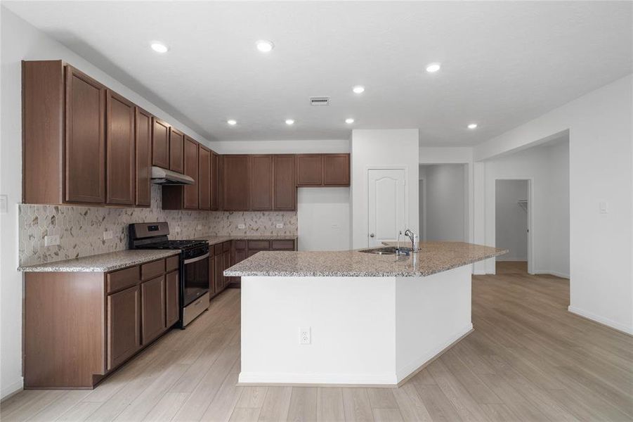 This spacious kitchen features high ceilings, stained wood cabinets, granite countertops, SS appliances, modern tile backsplash, recessed lighting, huge granite kitchen island with large single sink and space for breakfast bar, and a pantry all overlooking your huge family room.