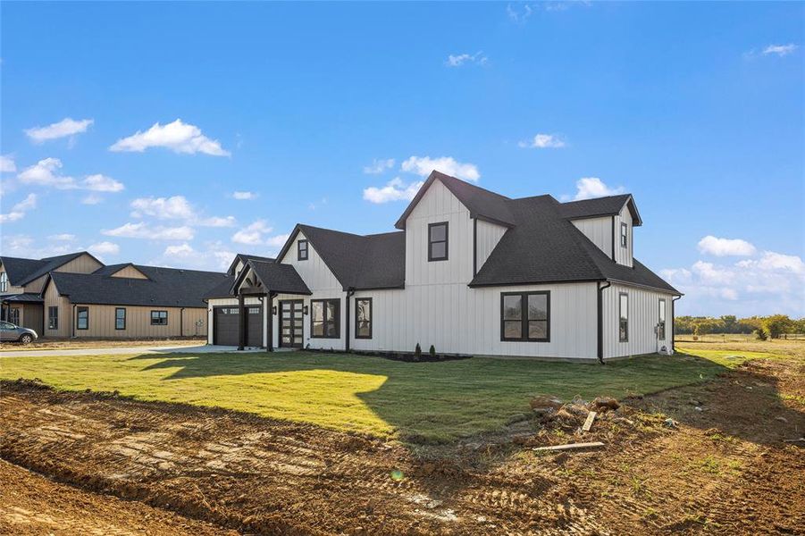 Back of house with a yard and a garage