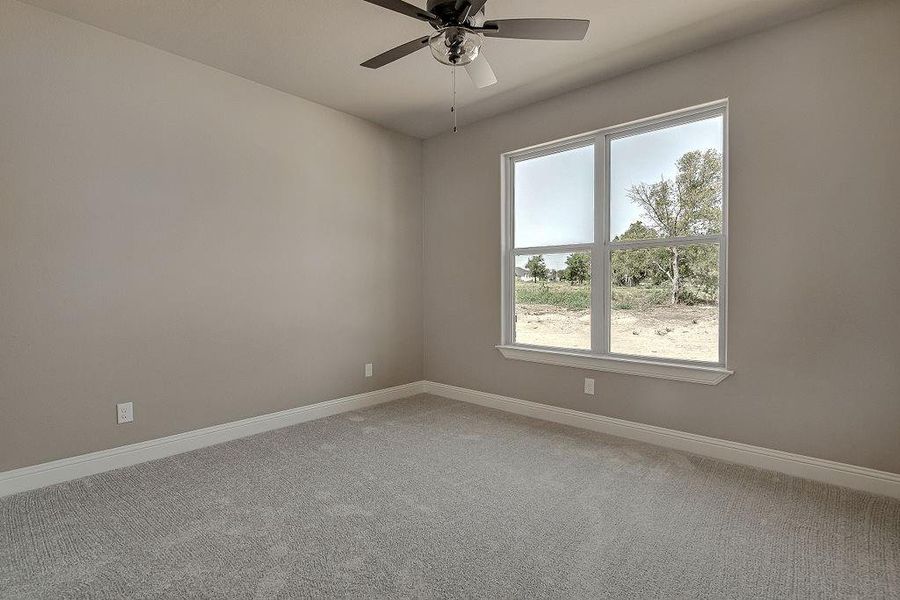 Carpeted empty room featuring ceiling fan