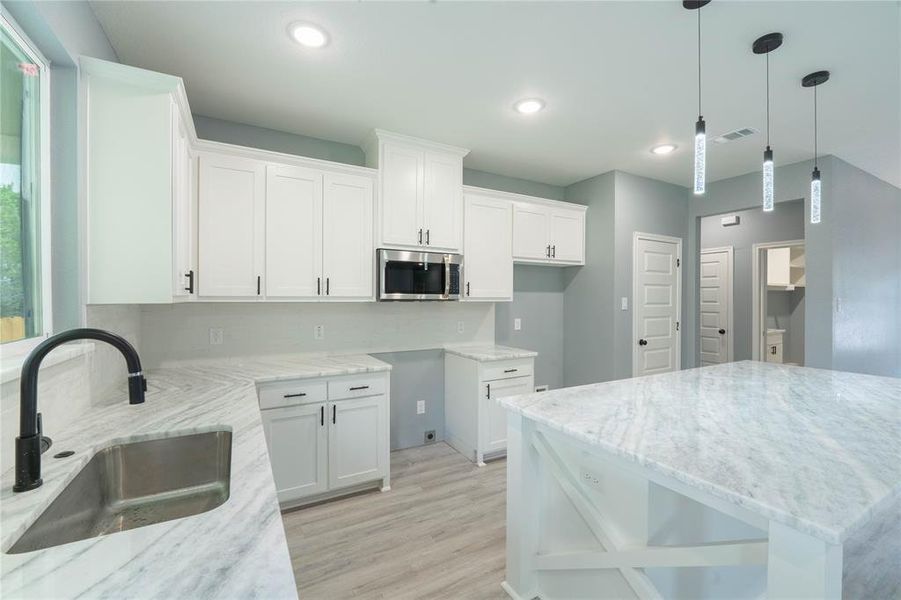 Kitchen featuring sink, light hardwood / wood-style flooring, light stone counters, and white cabinetry