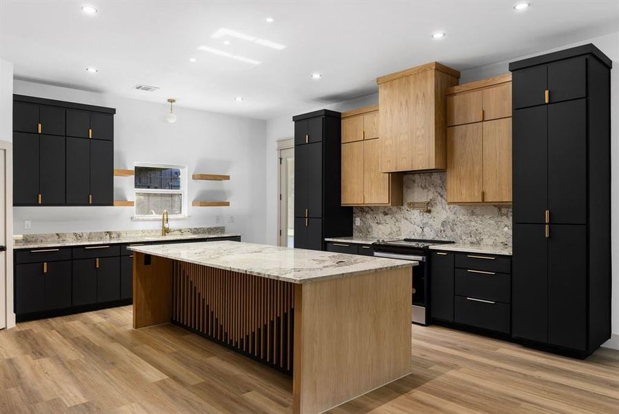 Kitchen featuring stainless steel stove, light brown cabinets, light hardwood / wood-style floors, and a kitchen island