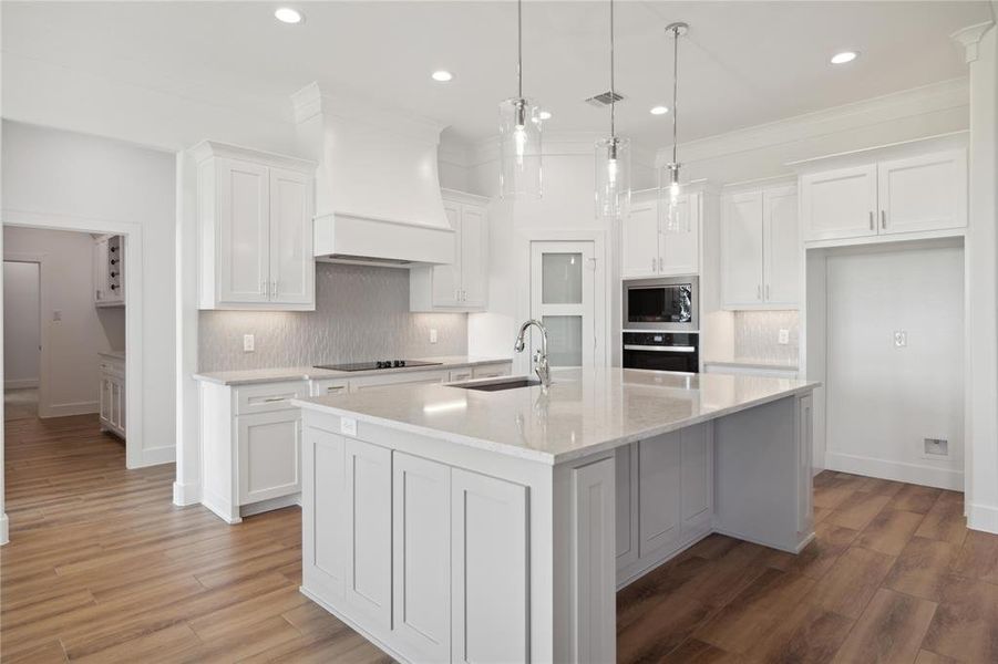 Kitchen with white cabinets, sink, an island with sink, and stainless steel appliances