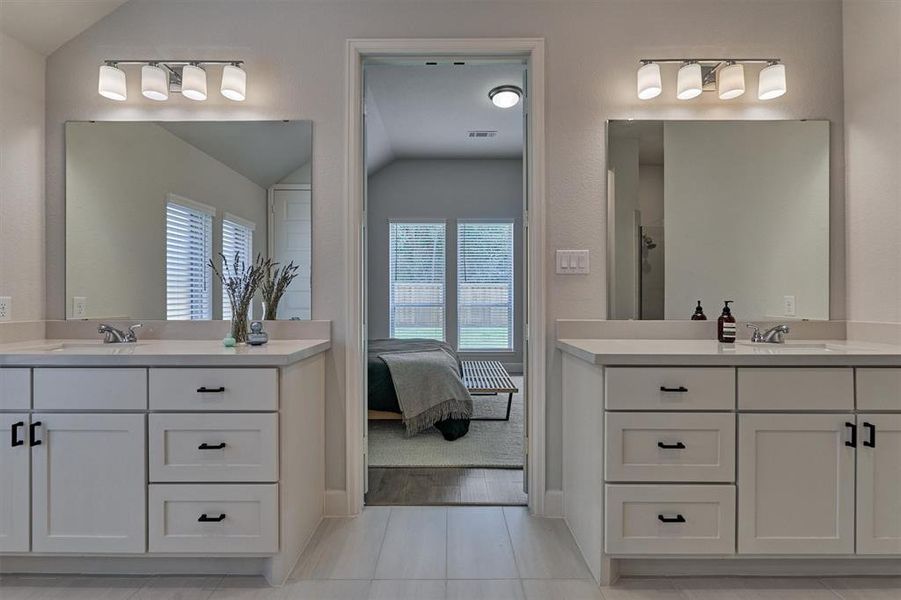 Quartz counters and upgraded hardware highlight dual raised vanities in the primary bath.