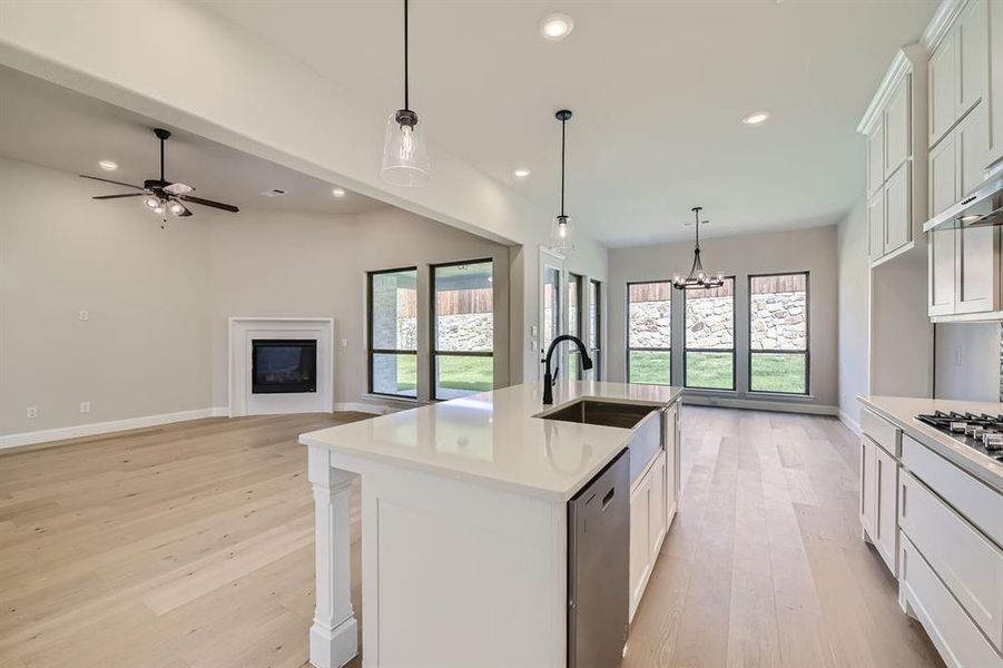 Kitchen featuring light hardwood / wood-style floors, stainless steel dishwasher, a wealth of natural light, and an island with sink