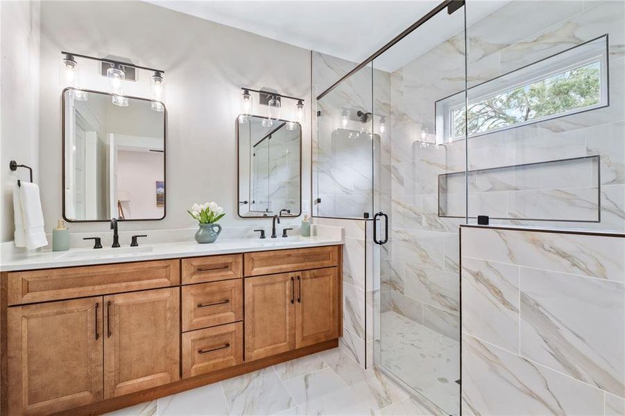 The owner's ensuite continues the neutral palette with custom porcelain tile work, dual sinks, walk-in shower, and separate toilet closet.