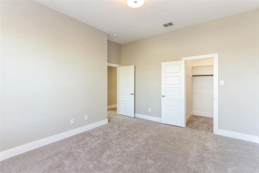 Unfurnished bedroom with a closet, light colored carpet, and a walk in closet