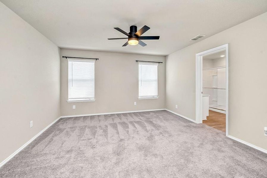 Unfurnished bedroom featuring ceiling fan, a spacious closet, and light carpet