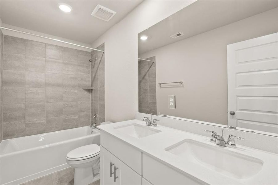 Second floor bathroom upstairs offers sleek countertop, double sinks, built-in cabinetry and tub/shower combo with tile surround.