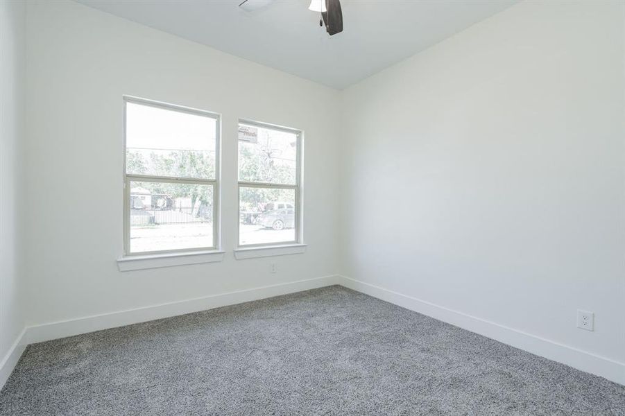 Carpeted spare room featuring plenty of natural light and ceiling fan