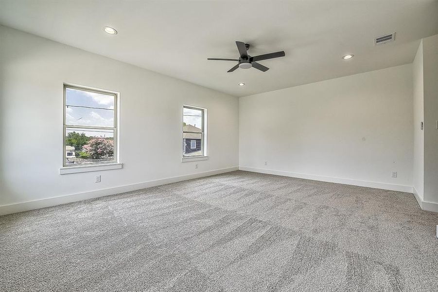 Carpeted spare room with plenty of natural light and ceiling fan