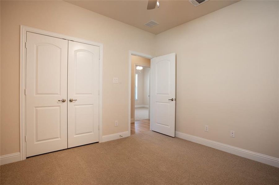 Unfurnished bedroom with light colored carpet, a closet, and ceiling fan