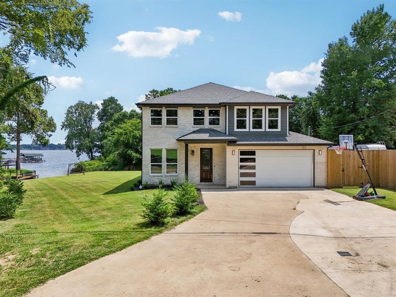 View of front of house with a water view and a front lawn