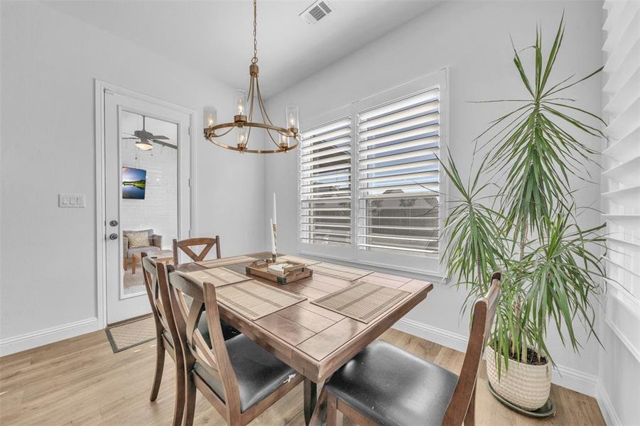 Dining space with ceiling fan with notable chandelier and light hardwood / wood-style flooring