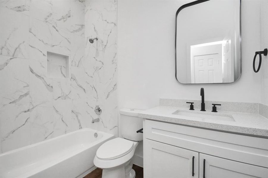 Full bathroom with a shower/tub combo and a lovely vanity with silestone countertops.