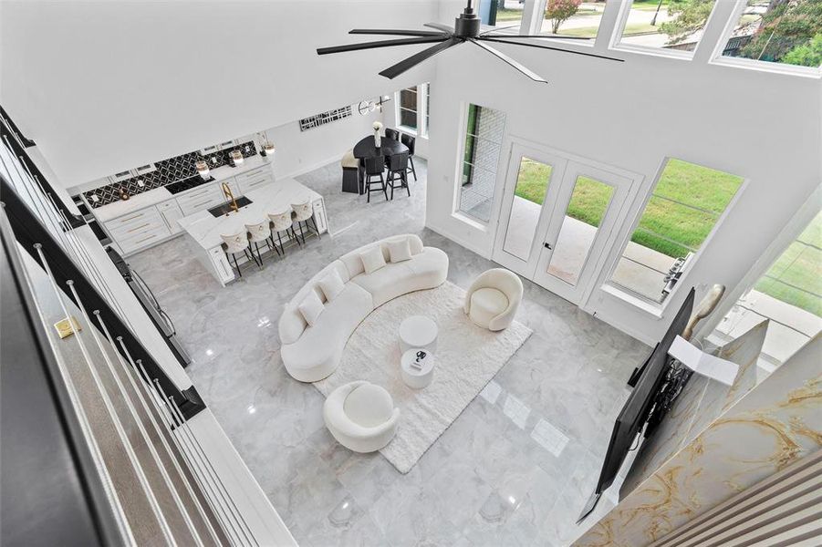 Living room with a high ceiling, ceiling fan, a healthy amount of sunlight, and sink