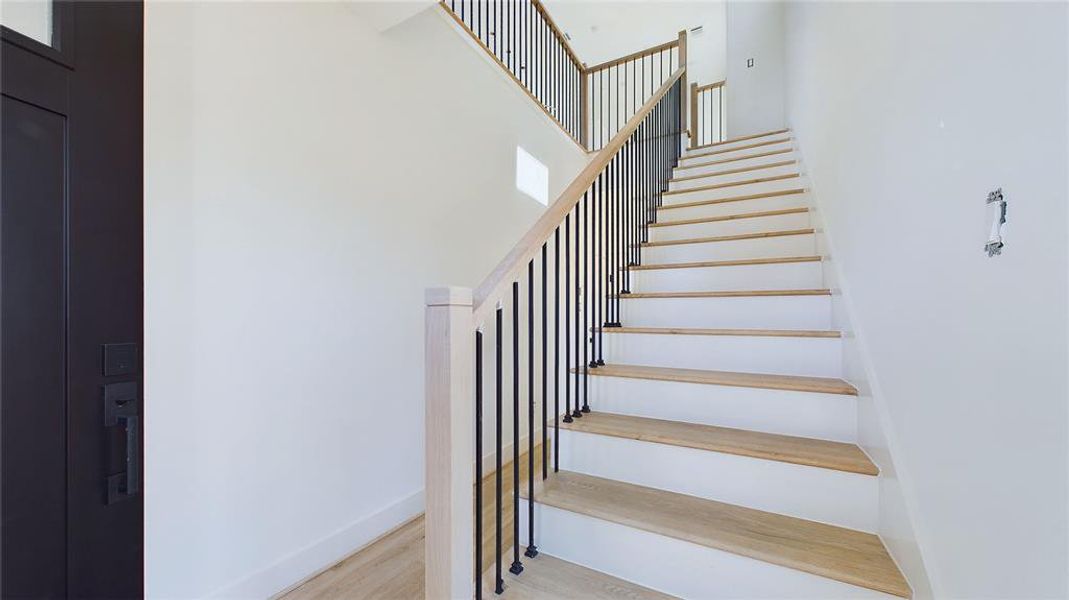 The staircase leading to the second floor features oak hardwood treads and is elegantly lined with sleek black metal balusters.