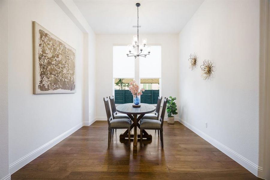 Dining area featuring dark wood-type flooring and an inviting chandelier