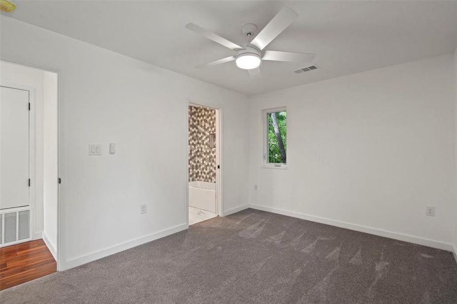 Unfurnished bedroom featuring ensuite bathroom, carpet floors, and ceiling fan